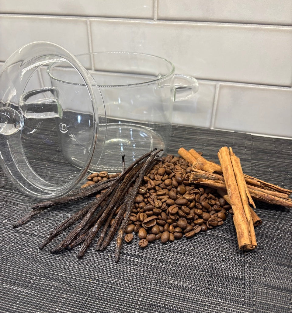 Clear glass mug with vanilla beans, coffee beans, and cinnamon sticks in a simmer pot